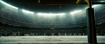 Movie still from “Invincible” (2006), directed by Ericson Core – A group of people standing on top of a football field; Extreme Wide shot, High angle