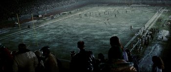 Movie still from “Invincible” (2006), directed by Ericson Core – A group of people standing on top of a dirt field; Extreme Wide shot, High angle