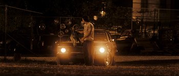 Movie still from “Invincible” (2006), directed by Ericson Core – A man standing in front of a car at night; Wide shot, Over the shoulder angle