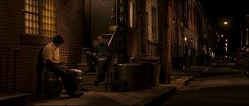 Movie still from “Invincible” (2006), directed by Ericson Core – A man sitting on the steps of a building at night; Wide shot, High angle