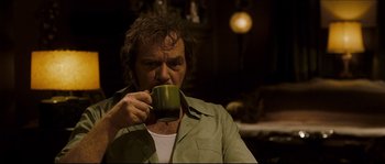Movie still from “Invincible” (2006), directed by Ericson Core – A man holding a green mug in his hand; Medium shot, Low angle