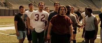 Movie still from “Invincible” (2006), directed by Ericson Core – A group of men standing next to each other in front of a bleachers; Medium shot, Low angle