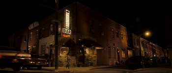 Movie still from “Invincible” (2006), directed by Ericson Core – A man walking down the sidewalk in front of a bar; Extreme Wide shot, Low angle