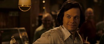 Movie still from “Invincible” (2006), directed by Ericson Core – A person wearing headphones and smiling; Close Up shot, Over the shoulder angle