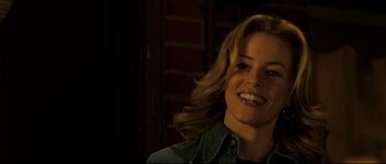 Movie still from “Invincible” (2006), directed by Ericson Core – A woman smiling for the camera in front of a brick wall; Close Up shot, Over the shoulder angle