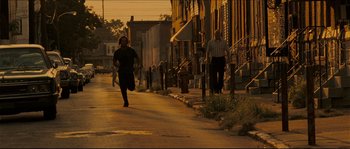 Movie still from “Invincible” (2006), directed by Ericson Core – A man running down the side of the street; Wide shot, Over the shoulder angle