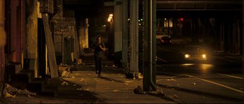 Movie still from “Invincible” (2006), directed by Ericson Core – A person walking down a street at night; Wide shot, Over the shoulder angle