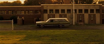 Movie still from “Invincible” (2006), directed by Ericson Core – An old car parked on the side of the road; Extreme Wide shot, Over the shoulder angle