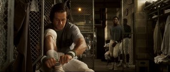 Movie still from “Invincible” (2006), directed by Ericson Core – A man sitting on a bench holding a baseball bat; Medium shot, Low angle