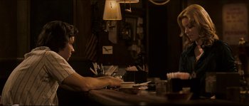 Movie still from “Invincible” (2006), directed by Ericson Core – A man sitting at a bar with a drink in his hand; Medium shot, Over the shoulder angle