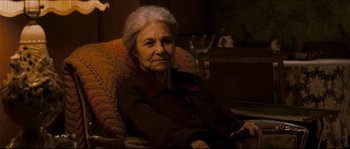 Movie still from “Invincible” (2006), directed by Ericson Core – An older woman sitting in a chair in a room; Close Up shot, High angle