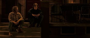Movie still from “Invincible” (2006), directed by Ericson Core – A man sitting on the steps of a house at night; Wide shot, Low angle