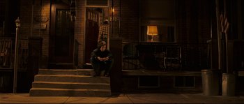 Movie still from “Invincible” (2006), directed by Ericson Core – A man sitting on the steps of a house at night; Wide shot, High angle