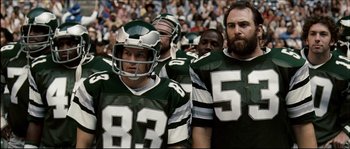 Movie still from “Invincible” (2006), directed by Ericson Core – A group of football players standing next to each other on a field; Medium shot, Low angle