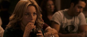 Movie still from “Invincible” (2006), directed by Ericson Core – A person drinking a drink at a table; Close Up shot, Over the shoulder angle