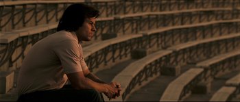 Movie still from “Invincible” (2006), directed by Ericson Core – A man sitting on a bench in front of a bunch of steps; Medium shot, High angle