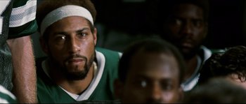 Movie still from “Invincible” (2006), directed by Ericson Core – A person with a bandage on his head; Close Up shot, Over the shoulder angle