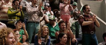 Movie still from “Invincible” (2006), directed by Ericson Core – A group of people sitting in a crowd clapping; Medium shot, Over the shoulder angle