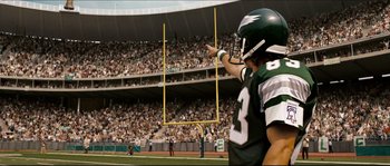 Movie still from “Invincible” (2006), directed by Ericson Core – A man in a football uniform points to the goal post; Medium shot, Overhead angle