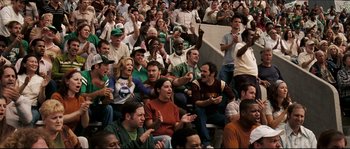 Movie still from “Invincible” (2006), directed by Ericson Core – A group of people sitting in the stands clapping; Medium shot, High angle
