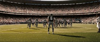Movie still from “Invincible” (2006), directed by Ericson Core – A group of football players standing on top of a football field; Extreme Wide shot, Low angle