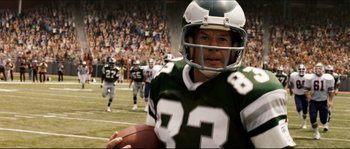 Movie still from “Invincible” (2006), directed by Ericson Core – A football player holding a football in front of a crowd; Close Up shot, Low angle
