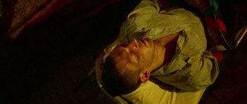 Movie still from “Irreversible” (2002), directed by Gaspar Noé – A man laying on the ground with his eyes closed; Extreme Close Up shot, Overhead angle