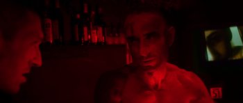 Movie still from “Irreversible” (2002), directed by Gaspar Noé – A man in a red room with bottles in the background; Close Up shot, Low angle