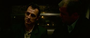 Movie still from “Irreversible” (2002), directed by Gaspar Noé – A man in a suit and tie next to another man in a suit and tie; Close Up shot, Over the shoulder angle