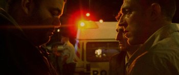 Movie still from “Irreversible” (2002), directed by Gaspar Noé – A group of men standing next to each other on a street; Close Up shot, Over the shoulder angle