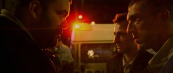 Movie still from “Irreversible” (2002), directed by Gaspar Noé – Two men talking to each other in front of a fire truck; Close Up shot, Over the shoulder angle