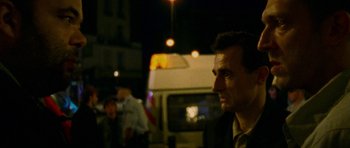 Movie still from “Irreversible” (2002), directed by Gaspar Noé – A person in a suit near a bus; Close Up shot, Over the shoulder angle