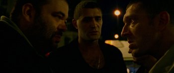 Movie still from “Irreversible” (2002), directed by Gaspar Noé – Two men standing next to each other in a dark room; Close Up shot, Over the shoulder angle