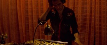 Movie still from “Irreversible” (2002), directed by Gaspar Noé – A man wearing headphones is playing a sound board; Medium shot, High angle