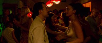 Movie still from “Irreversible” (2002), directed by Gaspar Noé – A man and a woman dancing in front of a crowd; Medium shot, Over the shoulder angle
