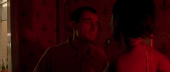 Movie still from “Irreversible” (2002), directed by Gaspar Noé – A man in a red shirt is standing in a room; Medium shot, Over the shoulder angle