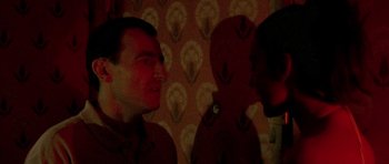 Movie still from “Irreversible” (2002), directed by Gaspar Noé – Two men are talking in a room with a floral wallpaper; Close Up shot, Over the shoulder angle