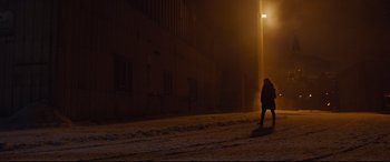 Movie still from “Jason Bourne” (2016), directed by Paul Greengrass – A person walking on a snowy sidewalk at night; Extreme Wide shot, Low angle