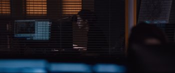 Movie still from “Jason Bourne” (2016), directed by Paul Greengrass – A man sitting at a desk in front of a computer monitor; Medium shot, High angle