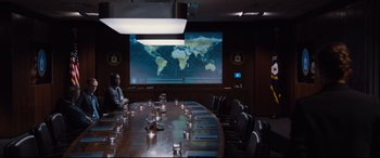 Movie still from “Jason Bourne” (2016), directed by Paul Greengrass – A man sitting in front of a projection screen in a conference room; Wide shot, Over the shoulder angle