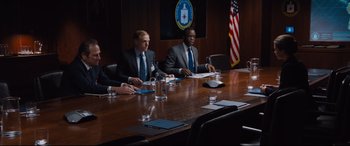 Movie still from “Jason Bourne” (2016), directed by Paul Greengrass – A group of men sitting at a table in a conference room; Medium shot, Over the shoulder angle