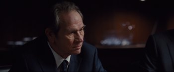 Movie still from “Jason Bourne” (2016), directed by Paul Greengrass – An older man wearing a suit and tie looking to his left; Close Up shot, Over the shoulder angle