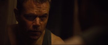 Movie still from “Jason Bourne” (2016), directed by Paul Greengrass – A man's face in a dark room; Close Up shot, Over the shoulder angle