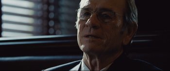 Movie still from “Jason Bourne” (2016), directed by Paul Greengrass – An older man wearing glasses and a suit; Close Up shot, Over the shoulder angle