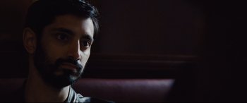 Movie still from “Jason Bourne” (2016), directed by Paul Greengrass – A person sitting on a couch; Close Up shot, Over the shoulder angle