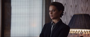 Movie still from “Jason Bourne” (2016), directed by Paul Greengrass – A woman wearing a suit and tie standing in front of a window; Close Up shot, Over the shoulder angle