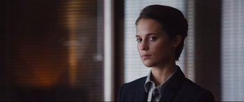 Movie still from “Jason Bourne” (2016), directed by Paul Greengrass – A woman wearing a suit and tie in front of a window; Close Up shot, Over the shoulder angle