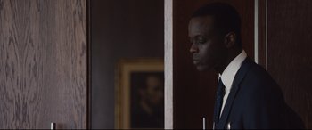 Movie still from “Jason Bourne” (2016), directed by Paul Greengrass – A man standing in front of a painting in a dark room; Close Up shot, Over the shoulder angle