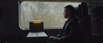 Movie still from “Jason Bourne” (2016), directed by Paul Greengrass – A man sitting on a train looking out the window; Medium shot, High angle
