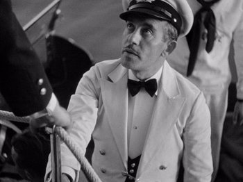 Movie still from “It Happened One Night” (1934), directed by Frank Capra – A man wearing a white suit and a hat; Medium shot, High angle